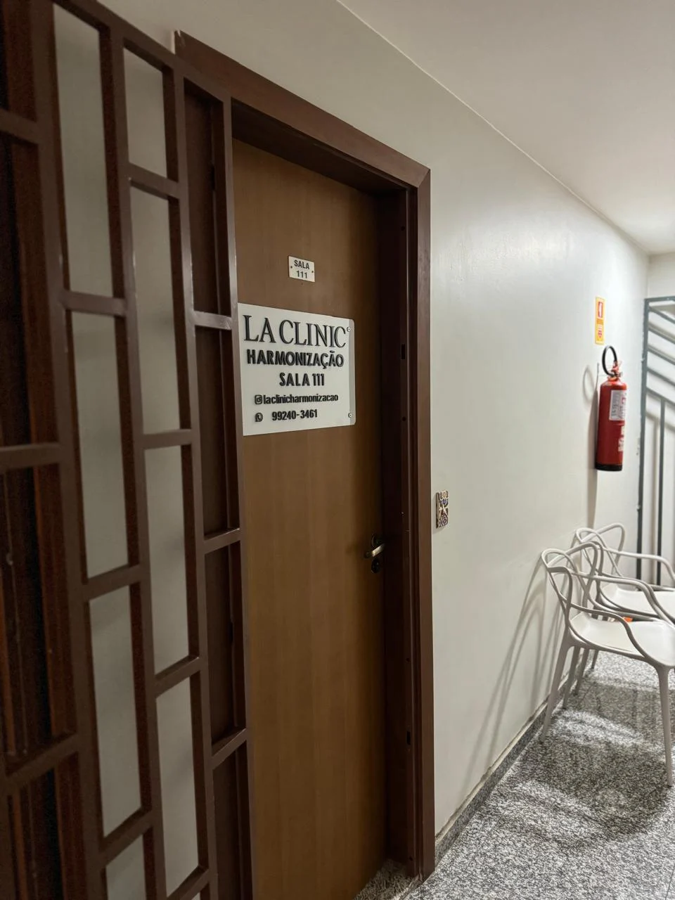 Porta de madeira da sala 111 com a placa branca LA CLINIC Harmonização